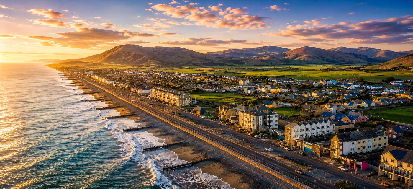 Aerial drone view of the beach, promenade and mountains at sunset